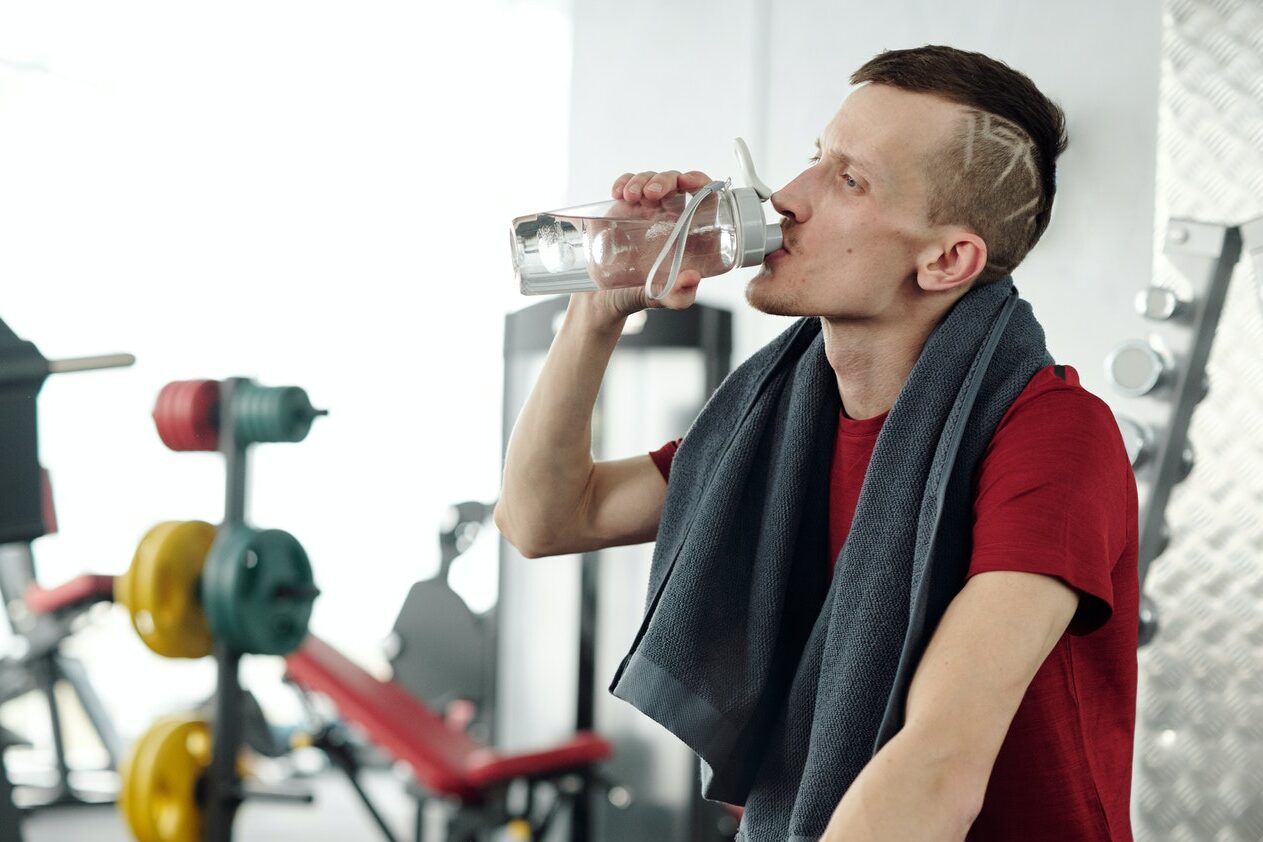 Mann in einem Fitnessstudio, welcher Wasser trinkt. Unsere Getränkebar hilft bei 